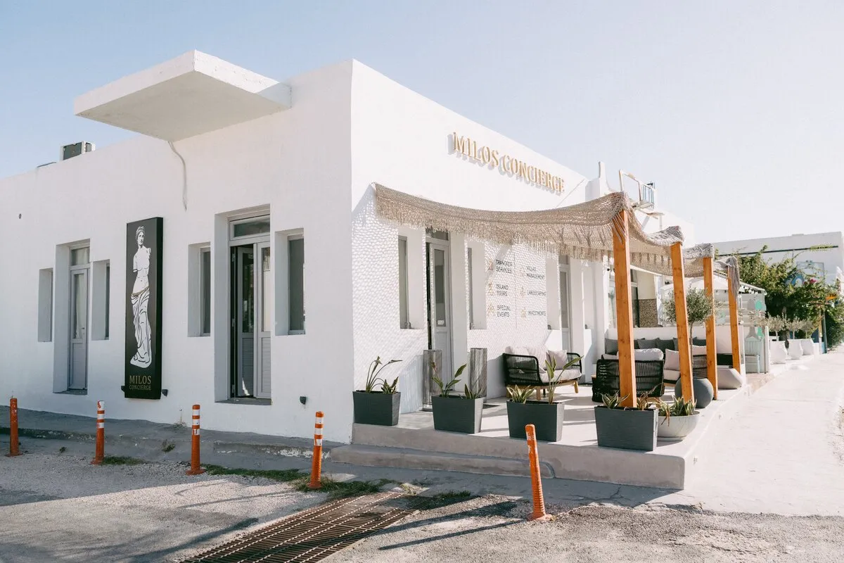 The front of the Milos Concierge office, with its sign and shaded terrace
